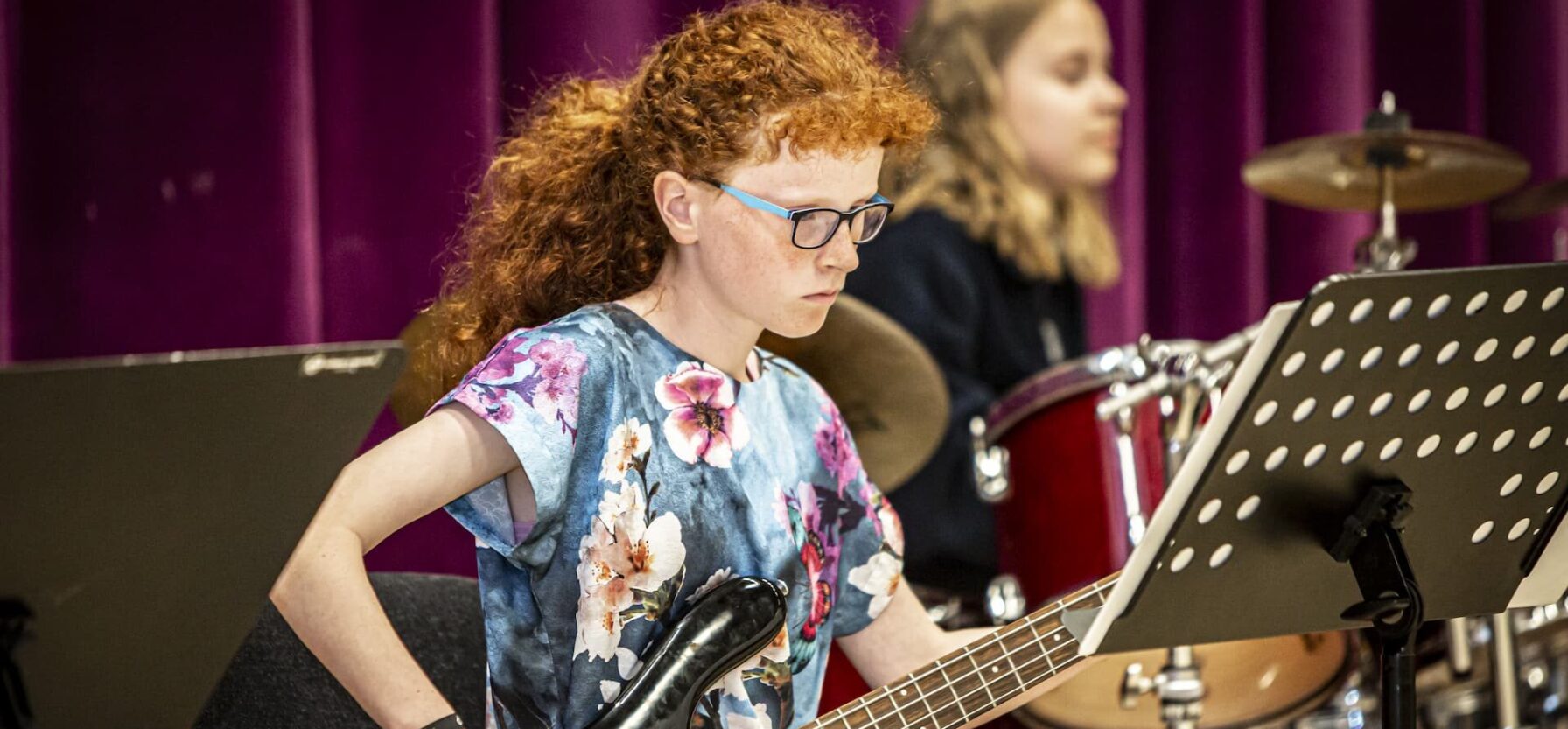 En rødhåret pige spiller bas til skolekoncert