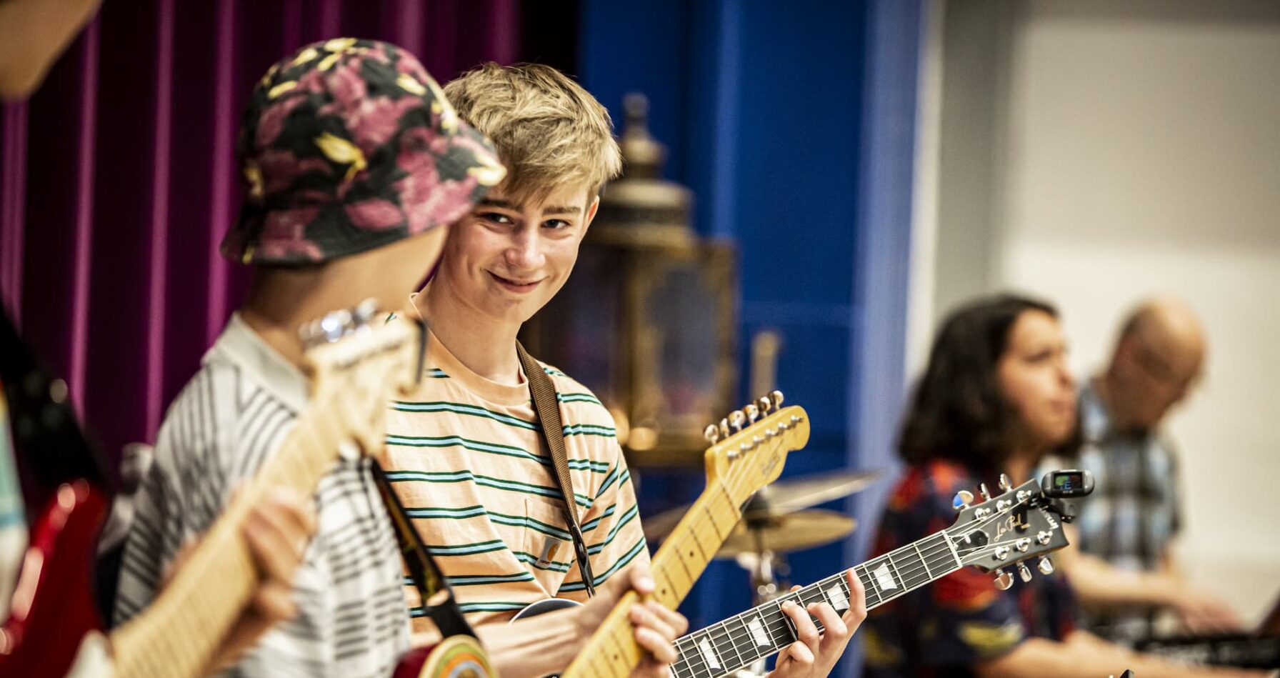 To drenge spiller elguitar og smiler til hinanden