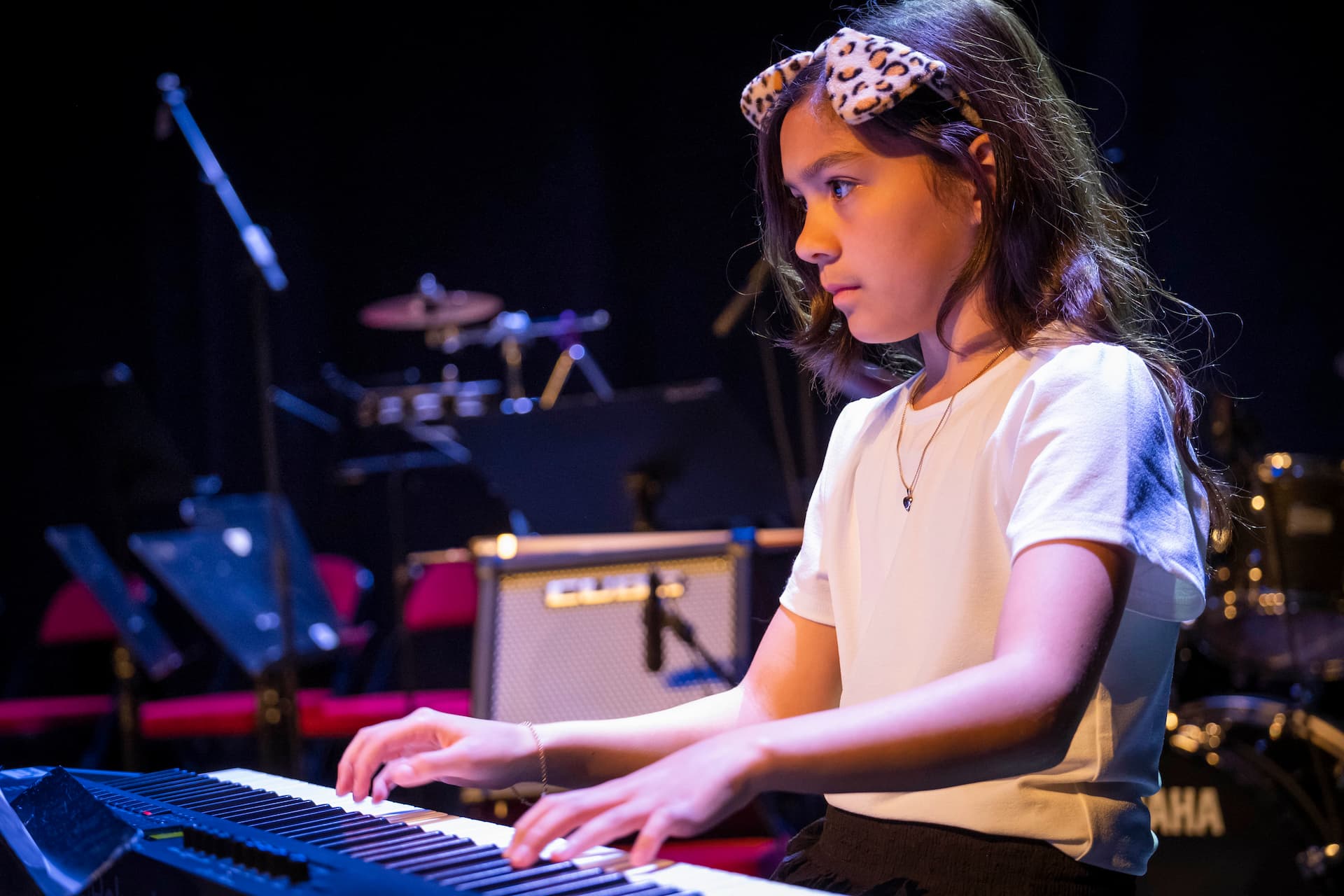 En pige spiller klaver og kigger koncentreret på sine noder