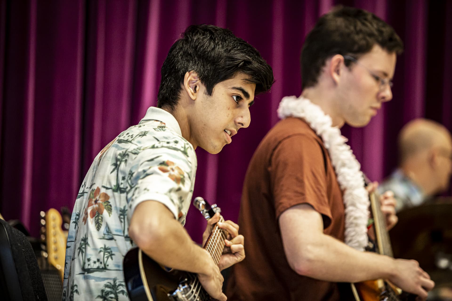 En dreng i hawaiiskjorte spiller elbas til koncert