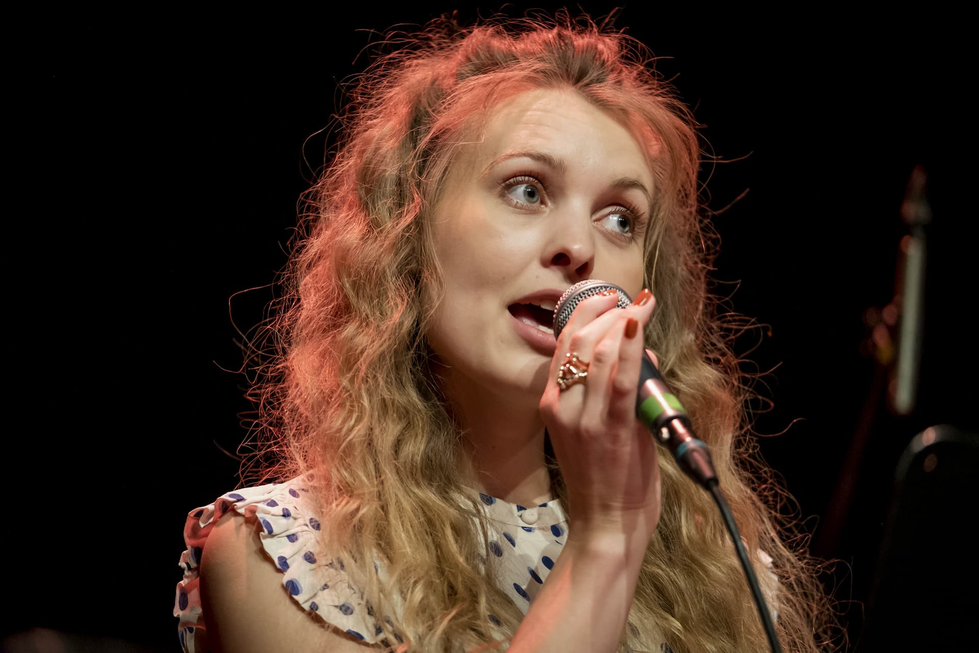 En lyshåret kvinde synger i mikrofon til koncert