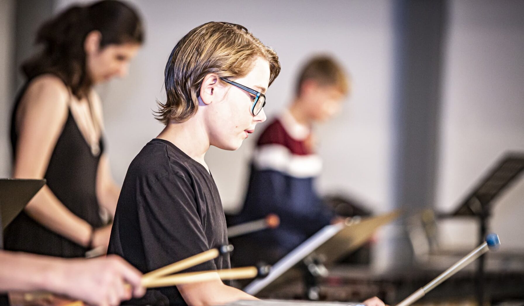 En dreng med briller spiller slagtøj til koncert sammen med andre elever