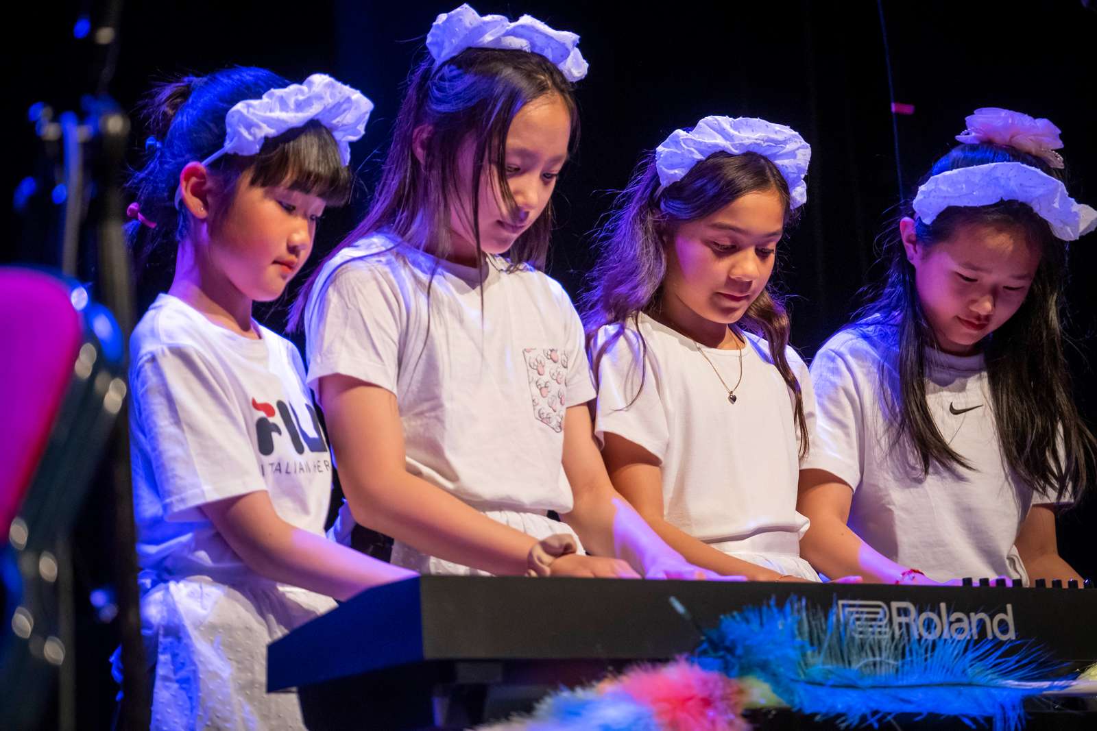 Fire små piger klædt ud som rengøringspersonale spiller firhændigt klaver til koncert